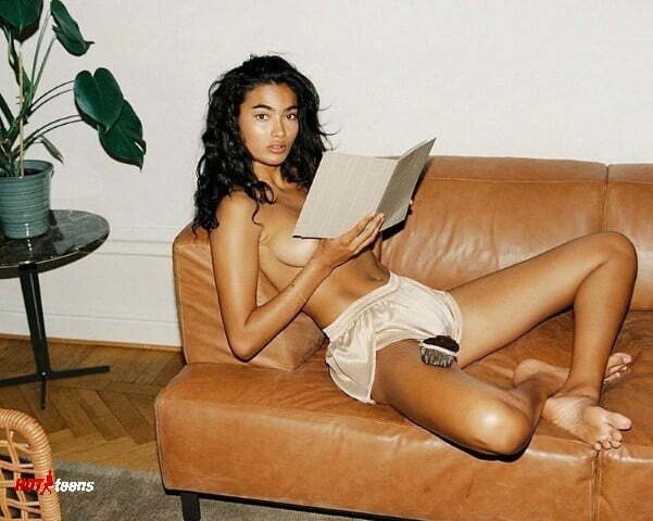 Kelly Gale reading a book nude on the sofa